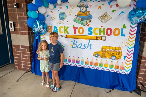 two students smiling under the back to school bash sign